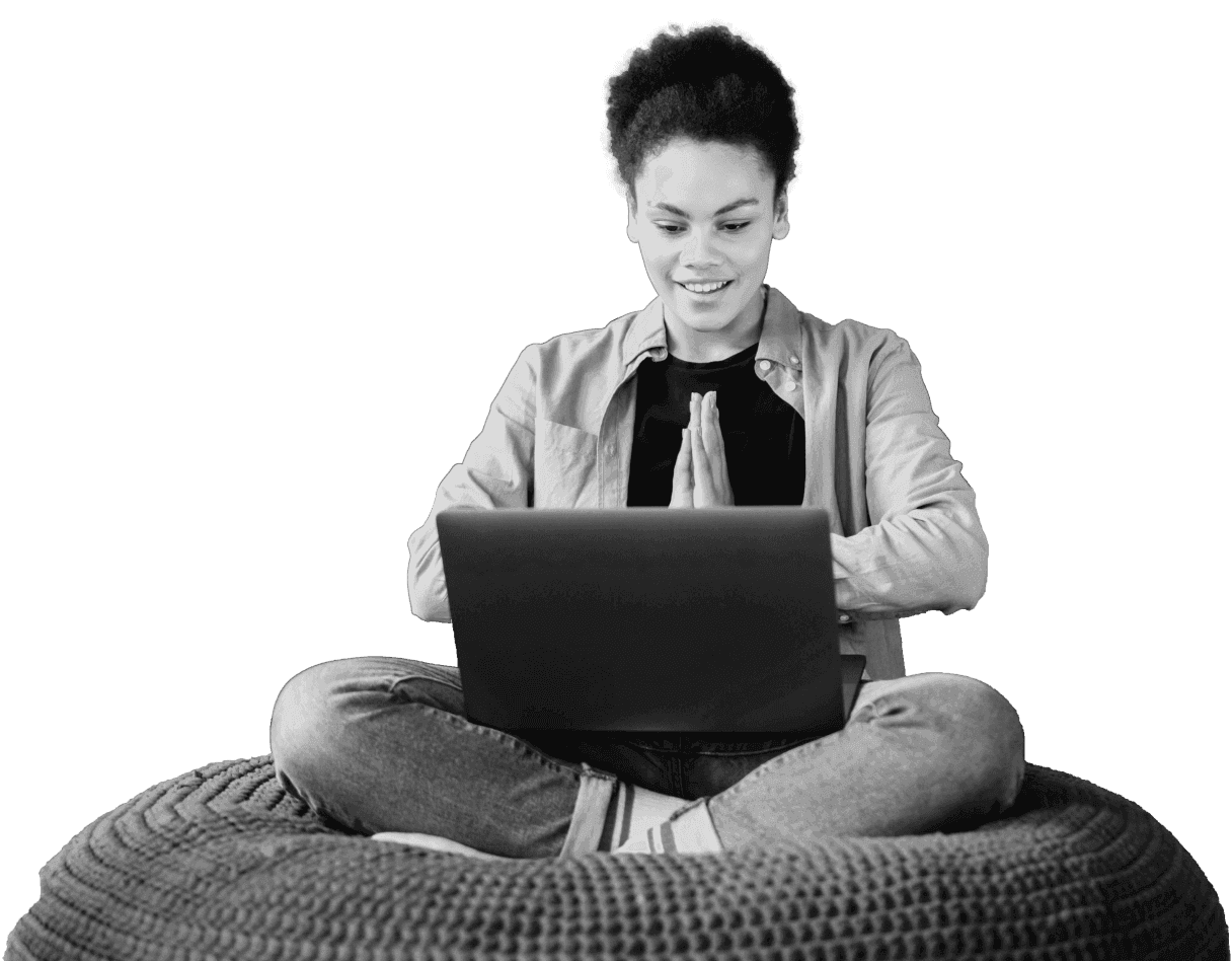 A person sitting cross-legged with a laptop, looking at the screen